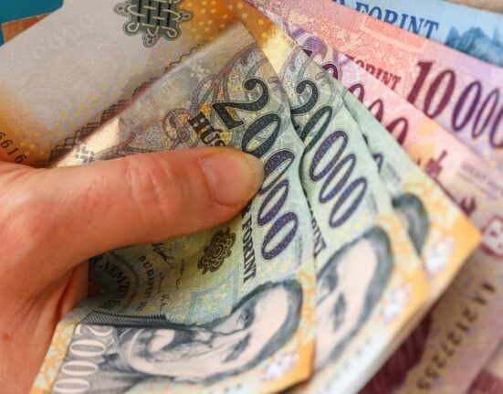 Egy szülő bankjegyet tart a kezében